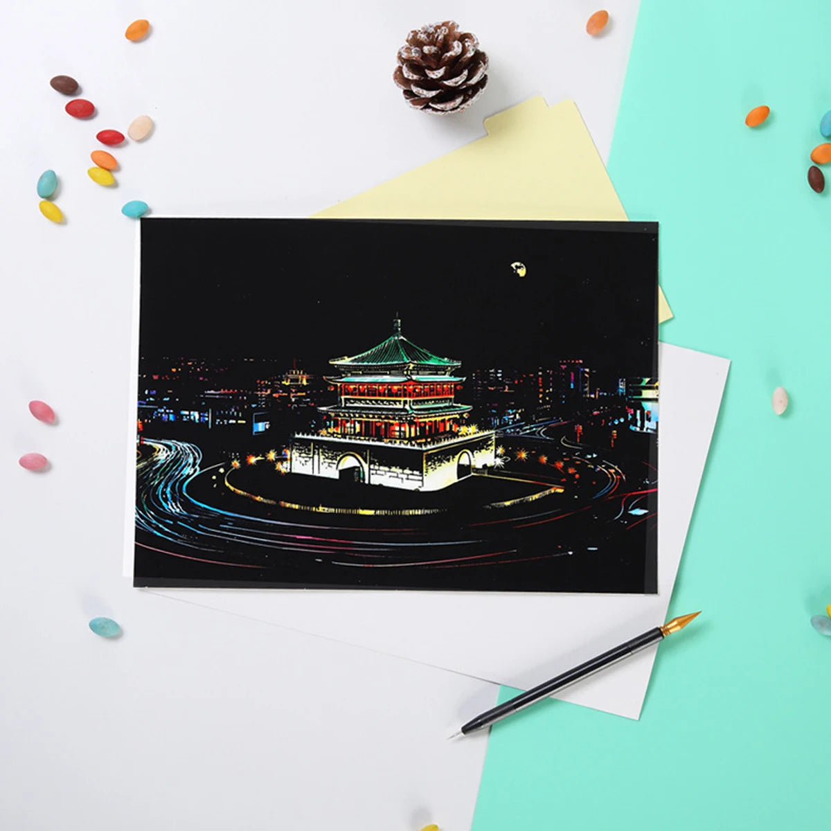 Scratch art board featuring a brightly lit ancient Chinese pavilion at night with colourful circular light trails.
