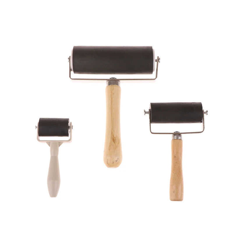 Three black craft brayer rollers in varying sizes with wooden and plastic handles, isolated on a white background.