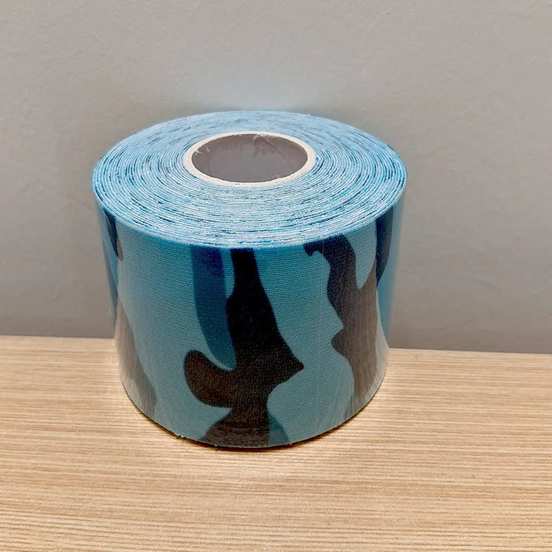 A single roll of blue kinesiology tape with a dark navy camouflage pattern, sitting on a wooden surface.
