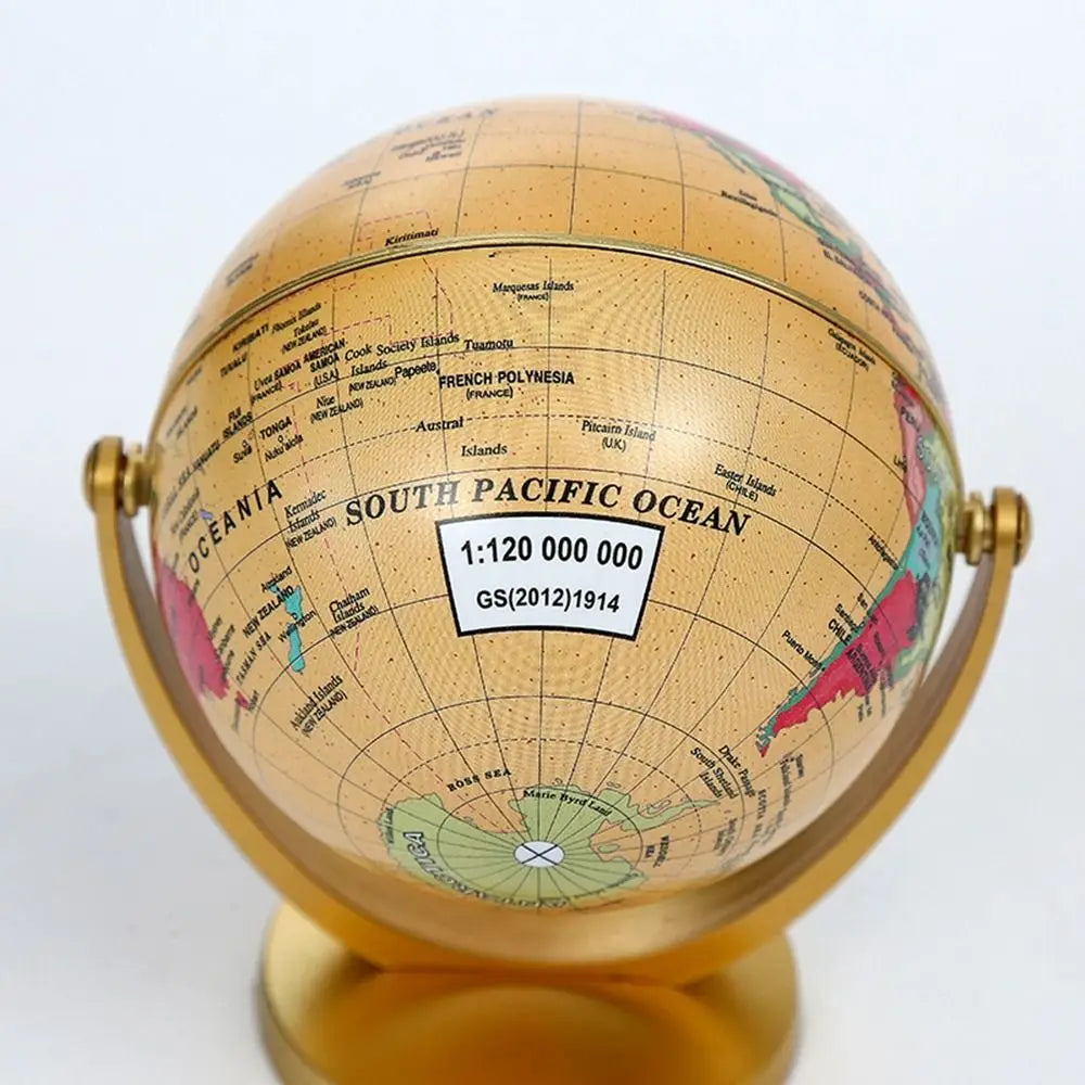 Decorative gold-toned world globe on a matching stand, featuring a detailed map of the South Pacific Ocean.