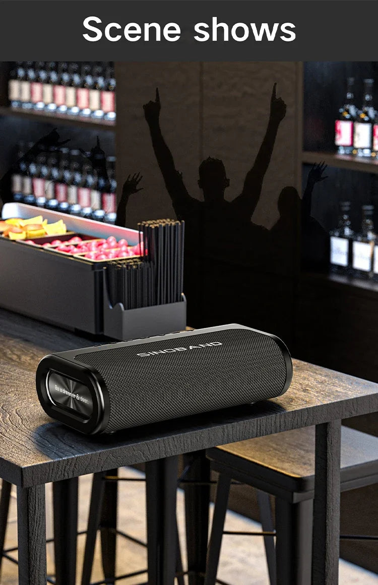 Black 80W portable Bluetooth speaker with a sleek, fabric-covered rectangular design, sitting on a bar table.