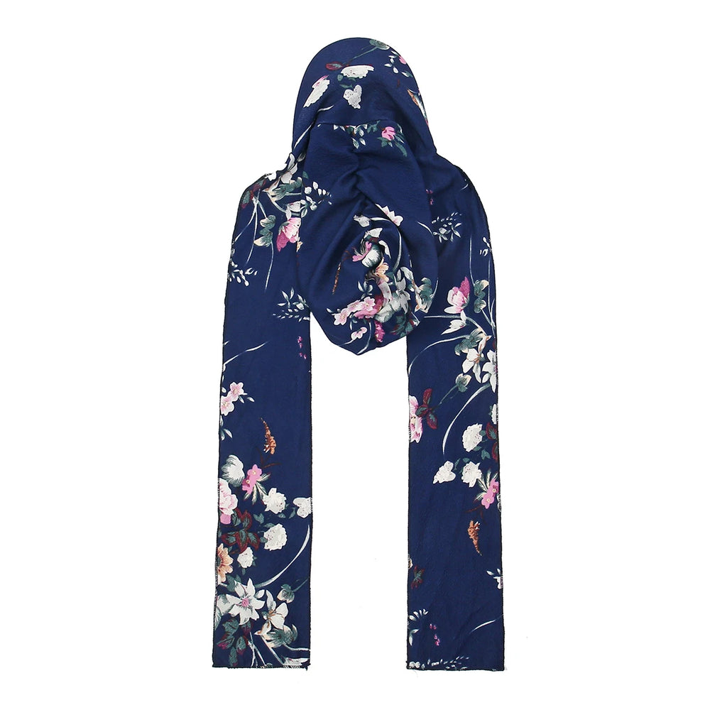 Navy blue floral turban hat with two long scarf ties, featuring a delicate white and pink blossom print.