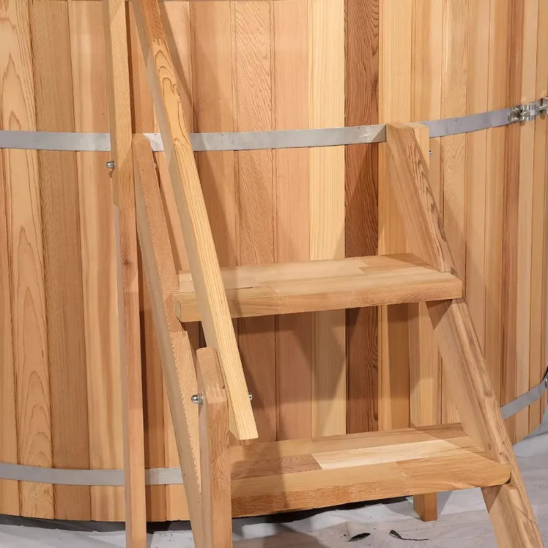 Wooden hot tub with two steps and a handrail attached, featuring metal bands.