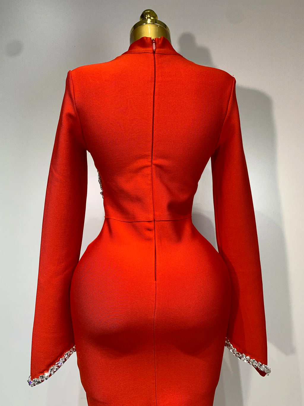 Back view of a red long-sleeve bodycon dress with rhinestone cuffs on a dress form.