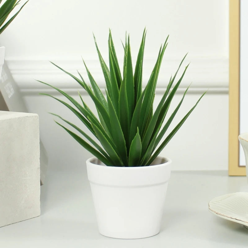 A faux, spiky green succulent plant potted in a simple white ceramic planter on a desk.