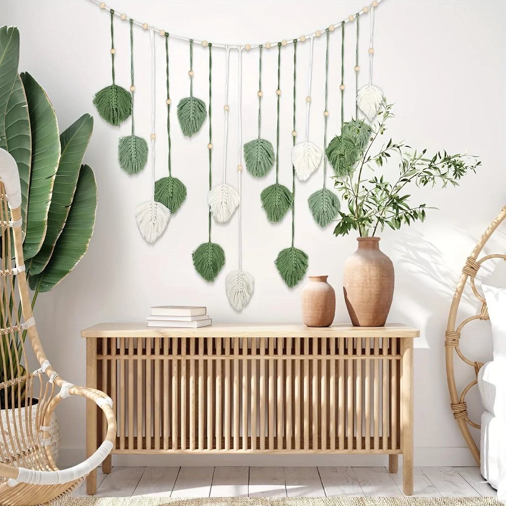 Boho macrame wall hanging featuring green and cream fabric leaves, wooden beads, and a natural rope design.