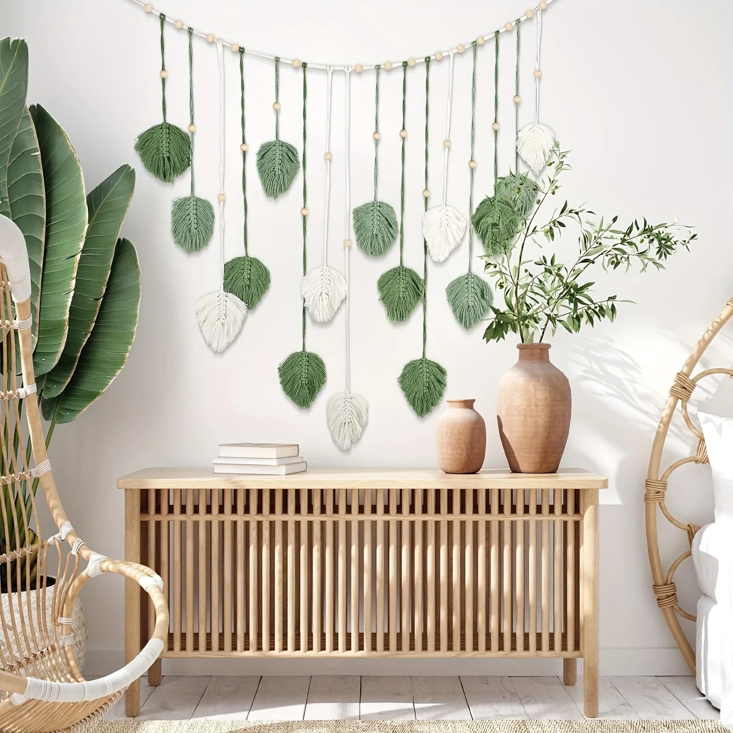 Boho macrame wall hanging featuring green and cream fabric leaves, wooden beads, and a natural rope design.