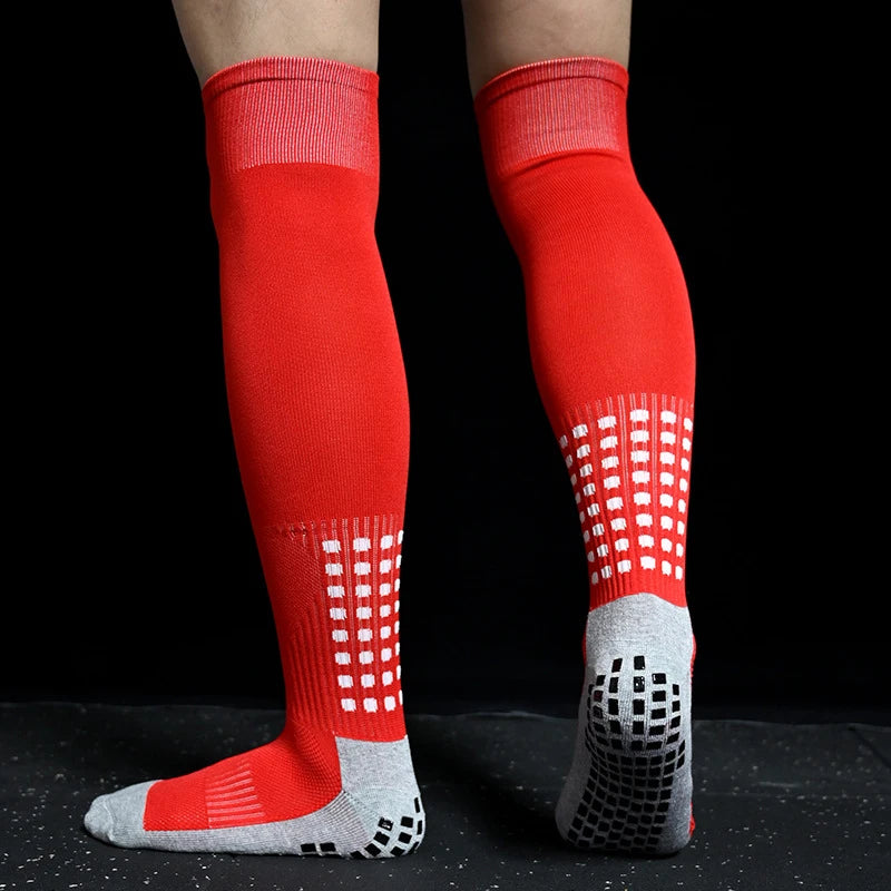 Red knee-high sports socks with white checkered pattern and grey grip-sole detailing, perfect for enhanced traction.