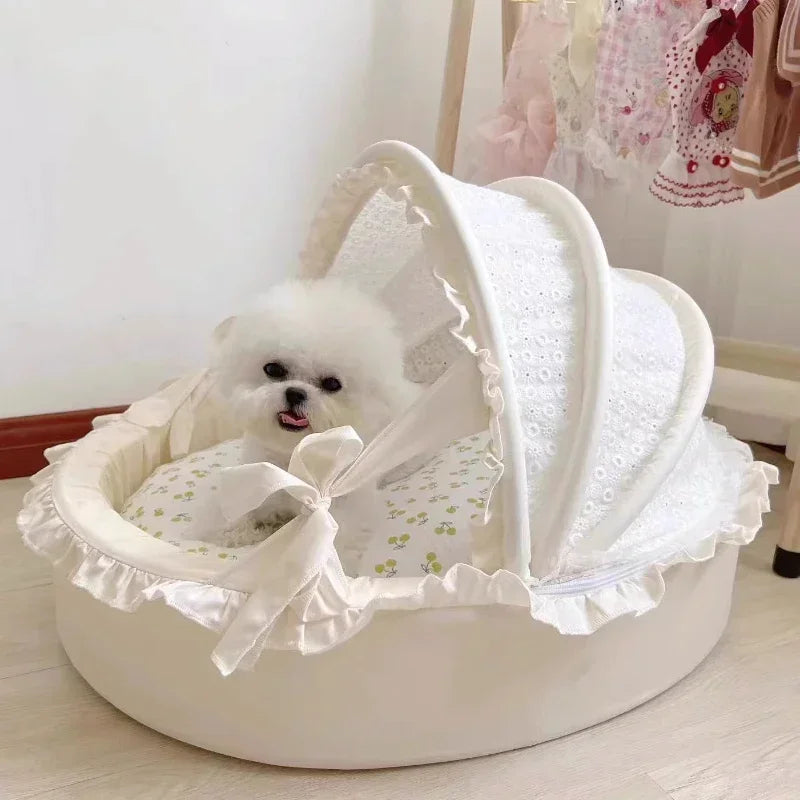 White round dog bed with lace canopy and ruffles, holding a small white fluffy dog inside.