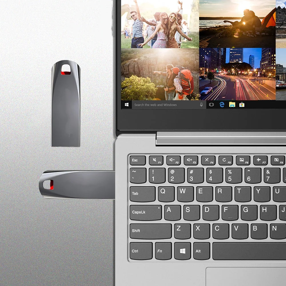 Sleek silver USB flash drive shown plugged into a laptop, with an additional unit displayed nearby.