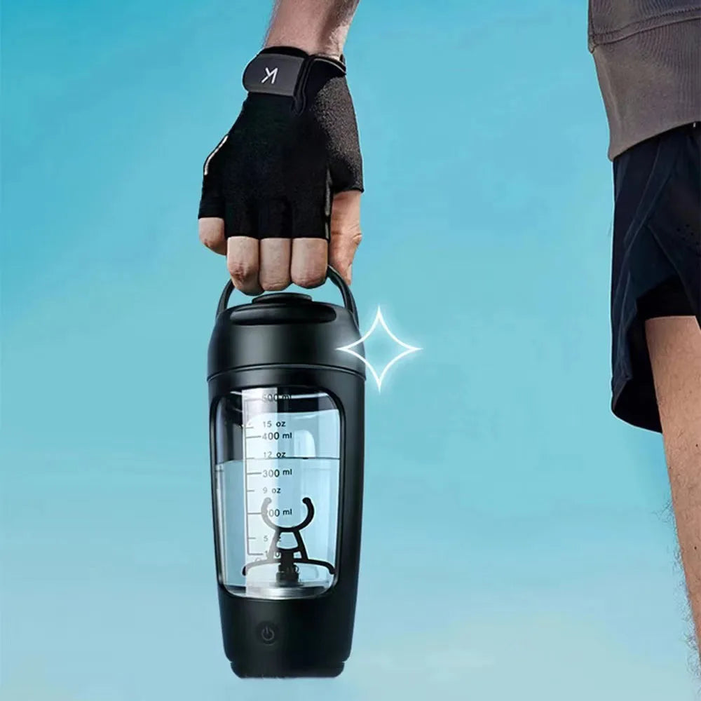A hand in a black glove holds a sleek, black electric shaker bottle with a clear measurement window.