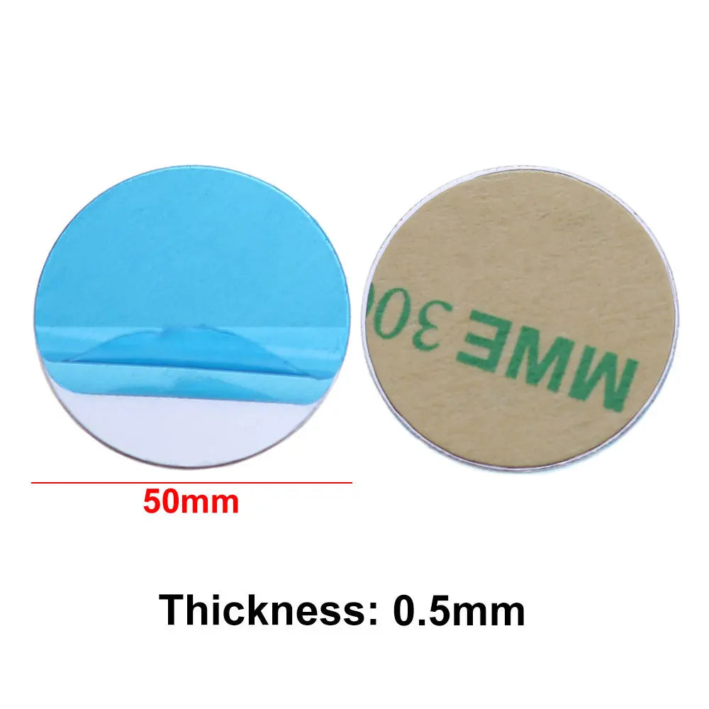 Two 50mm diameter adhesive metal discs, 0.5mm thick, shown with blue protective film and tan backing paper.