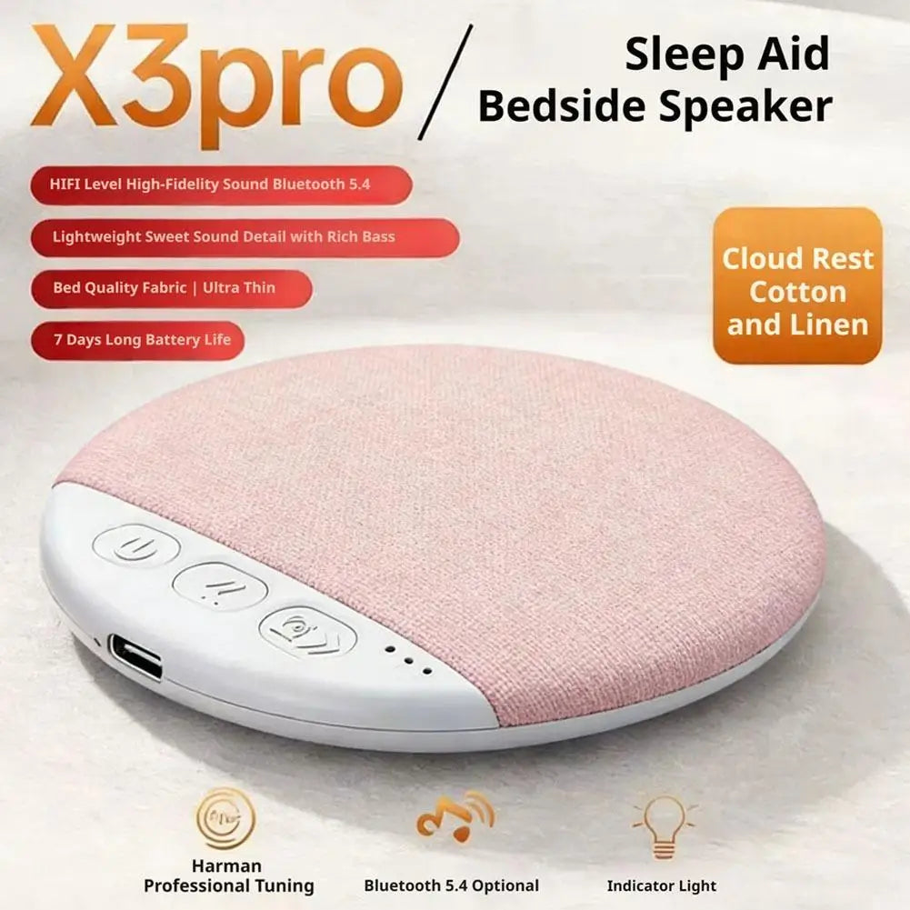 Ultra-thin, round, wireless under-pillow speaker in soft pink fabric with white control buttons and USB charging port.
