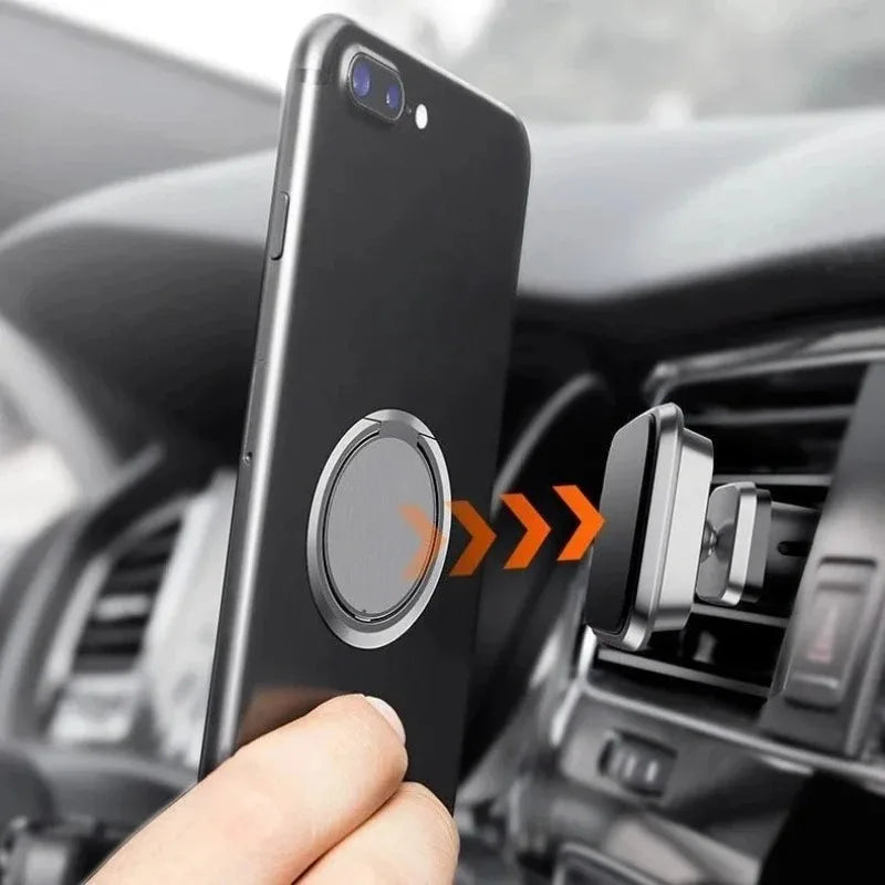 A black smartphone with a silver magnetic ring stand attaching to a silver air vent car phone mount.