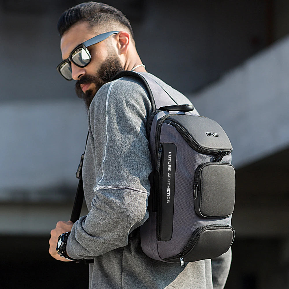 A man wearing a grey, multifunction anti-theft crossbody backpack with multiple zipped pockets and a sleek design.