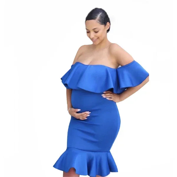 Pregnant woman in a royal blue, off-the-shoulder maternity dress with ruffled neckline and hemline.