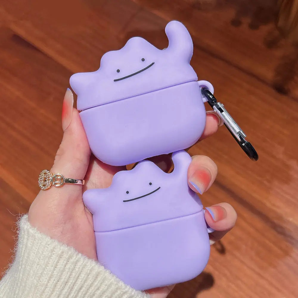 Purple silicone AirPods Pro case shaped like the Pokémon Ditto, featuring a character face and silver carabiner clip.
