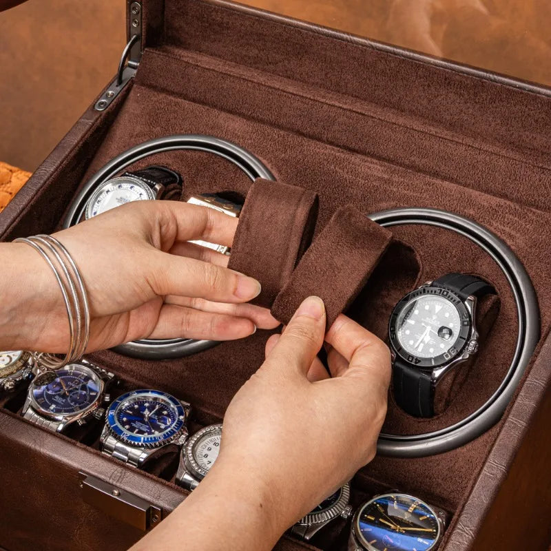 Brown leather watch winder box with soft velvet interior holding automatic wristwatches.
