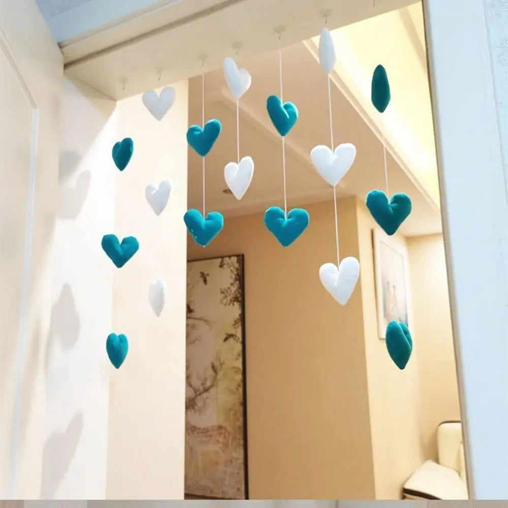 Hanging room decoration featuring teal and white plush fabric hearts suspended from strings in a doorway.