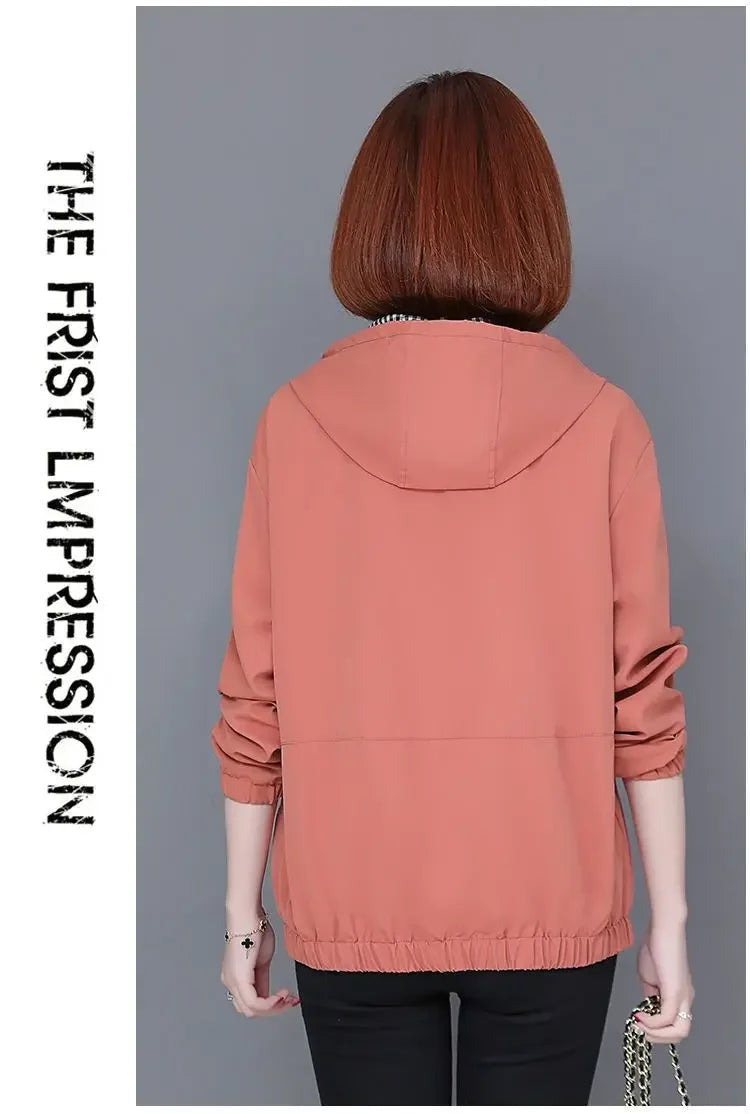 Back view of a woman wearing a dusty pink hooded windbreaker jacket with long sleeves and an elasticated hem.