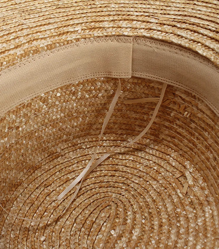Close-up view of the interior of a natural straw sun hat, showing the woven texture and an adjustable elastic band.
