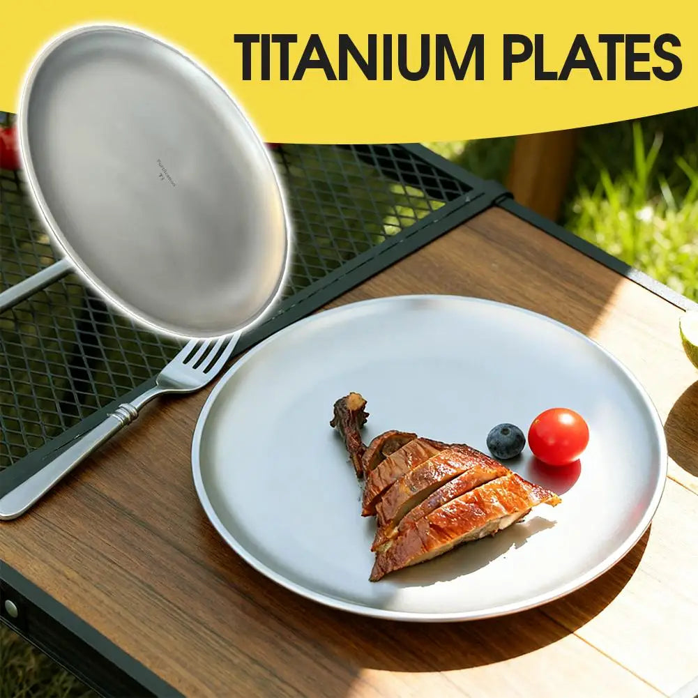Two round titanium plates on a wooden camping table with sliced meat, a blueberry, and a cherry tomato.