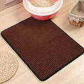 Brown rectangular cat litter mat with a honeycomb texture, featuring a black border on a wooden floor.