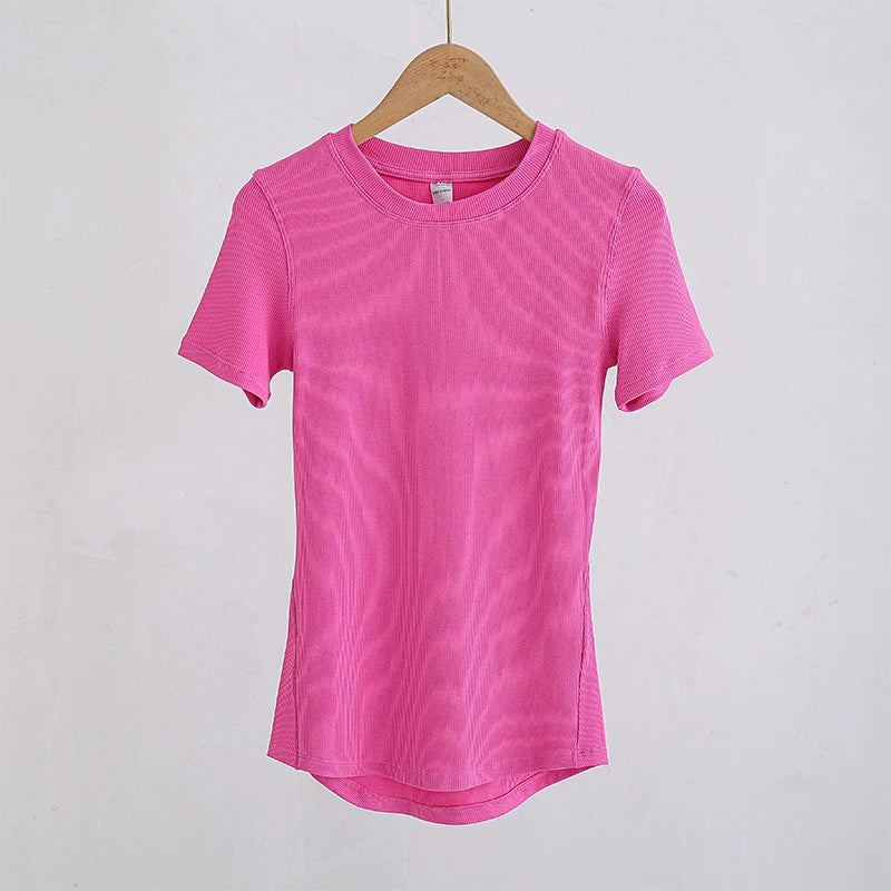 Hot pink ribbed crew-neck T-shirt with short sleeves and a curved hem, hanging on a wooden hanger.