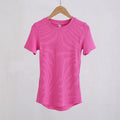 Hot pink ribbed crew-neck T-shirt with short sleeves and a curved hem, hanging on a wooden hanger.