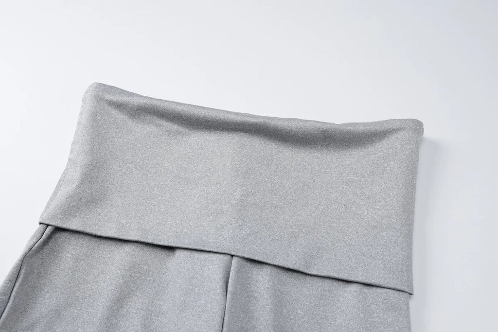 Close-up of grey high-waisted leggings featuring a wide, fold-over waistband in a soft, stretchy fabric.