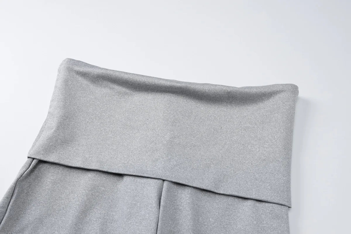 Close-up of grey high-waisted leggings featuring a wide, fold-over waistband in a soft, stretchy fabric.