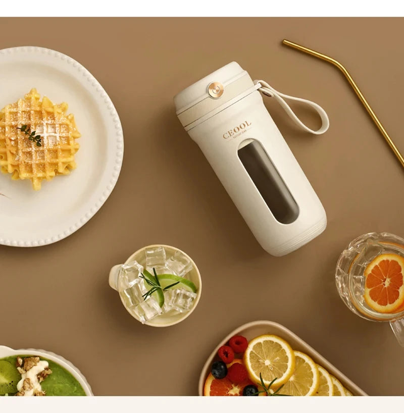 Cream-colored portable drink tumbler with a glass viewing window, carrying strap, and gold accent, on a brown surface.