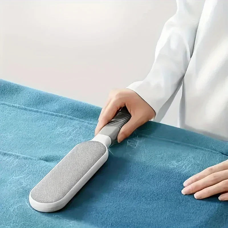 A white and grey lint remover tool being used to clean pet hair from a teal fabric surface.