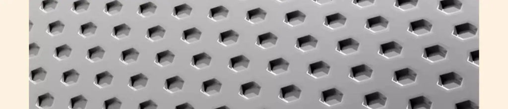 Close-up of a grey, heavy-duty cat litter mat featuring a textured hexagonal hole pattern to trap litter.