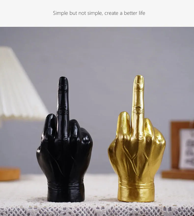 Black and gold hand-shaped table ornaments featuring a raised middle finger gesture with a smooth, modern finish.