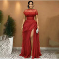 Red tulle evening dress with sheer short sleeves, ruched bodice, high slit, and ruffled skirt.