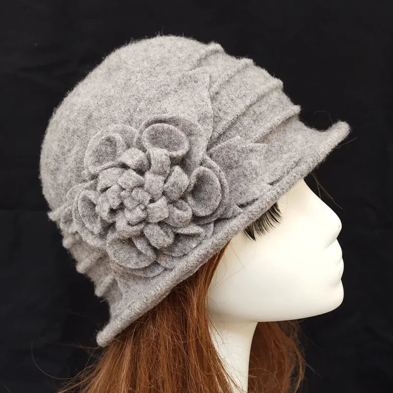Elegant grey felted wool winter hat with decorative flower detail and side pleats, shown on a mannequin head.