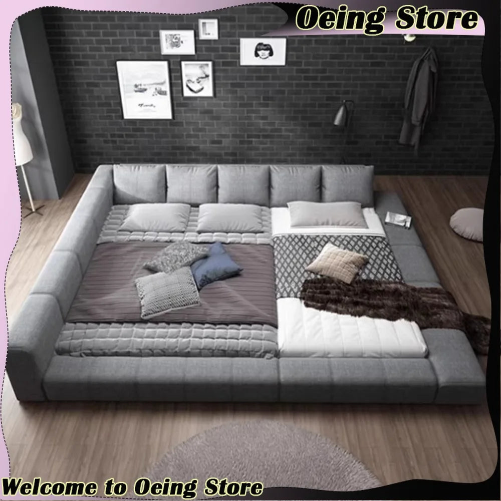 Modern, extra-large grey fabric double bed with a low-profile padded frame and integrated headboard cushions.
