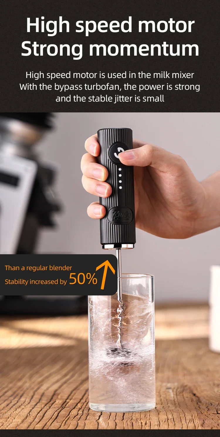 Handheld black milk frother with a textured, ribbed handle and power button, mixing liquid in a clear glass.