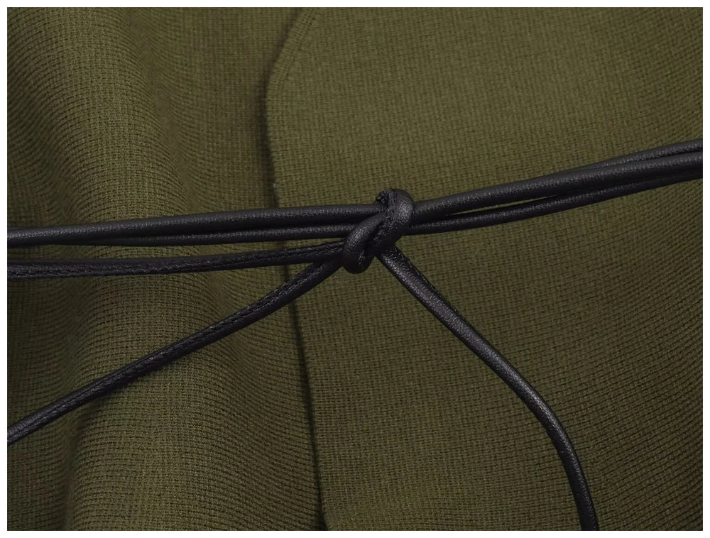 Close-up of an olive green knit garment cinched with a thin, black faux-leather cord tied in a simple knot.