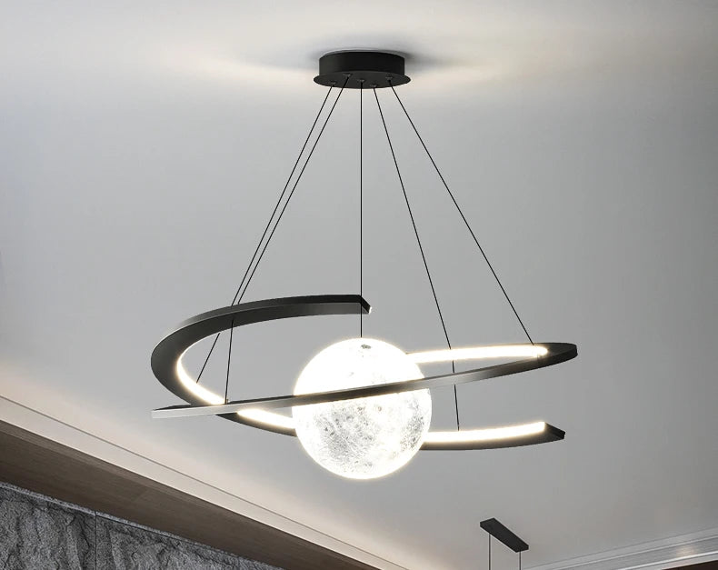 Modern black pendant light featuring an LED-lit ring encircling a glowing, textured moon-like sphere.