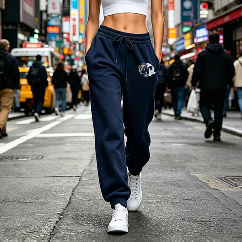 Navy blue joggers with an elastic drawstring waist and koi fish graphic, featuring a relaxed, cuffed-ankle fit.