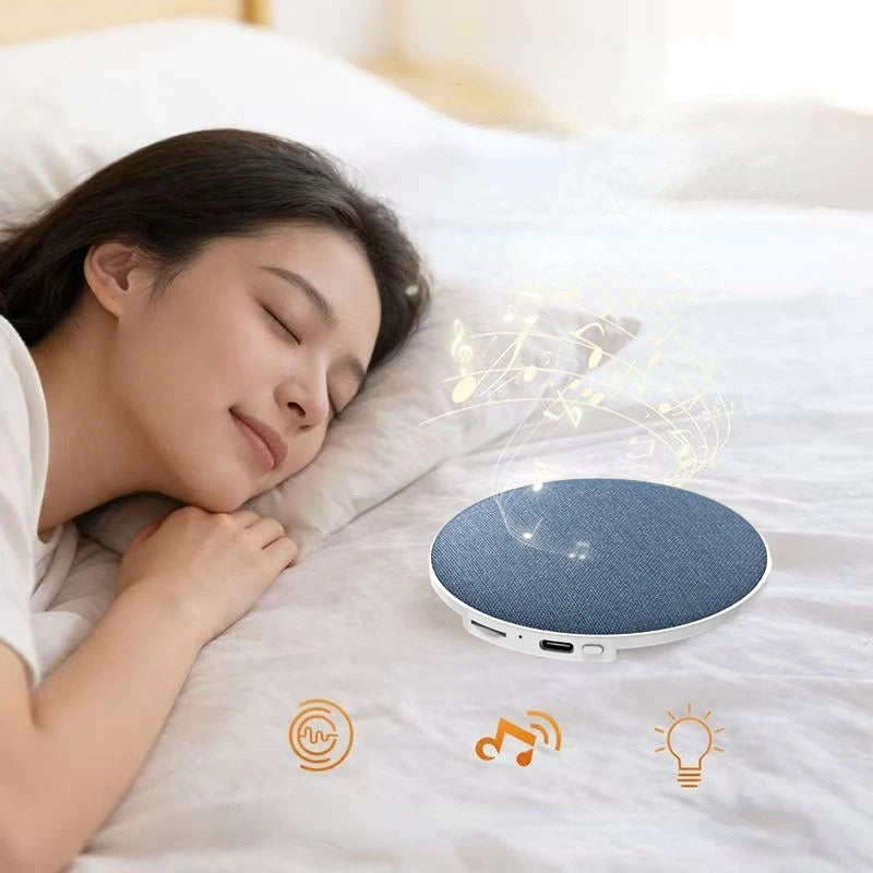 A round, blue fabric wireless speaker for under-pillow use, shown on a bed with musical note graphics.