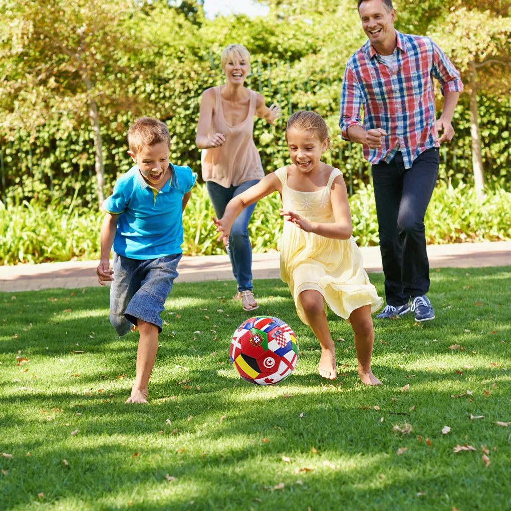 A vibrant football featuring a multicoloured print of international flags, resting on grass during a family garden game.