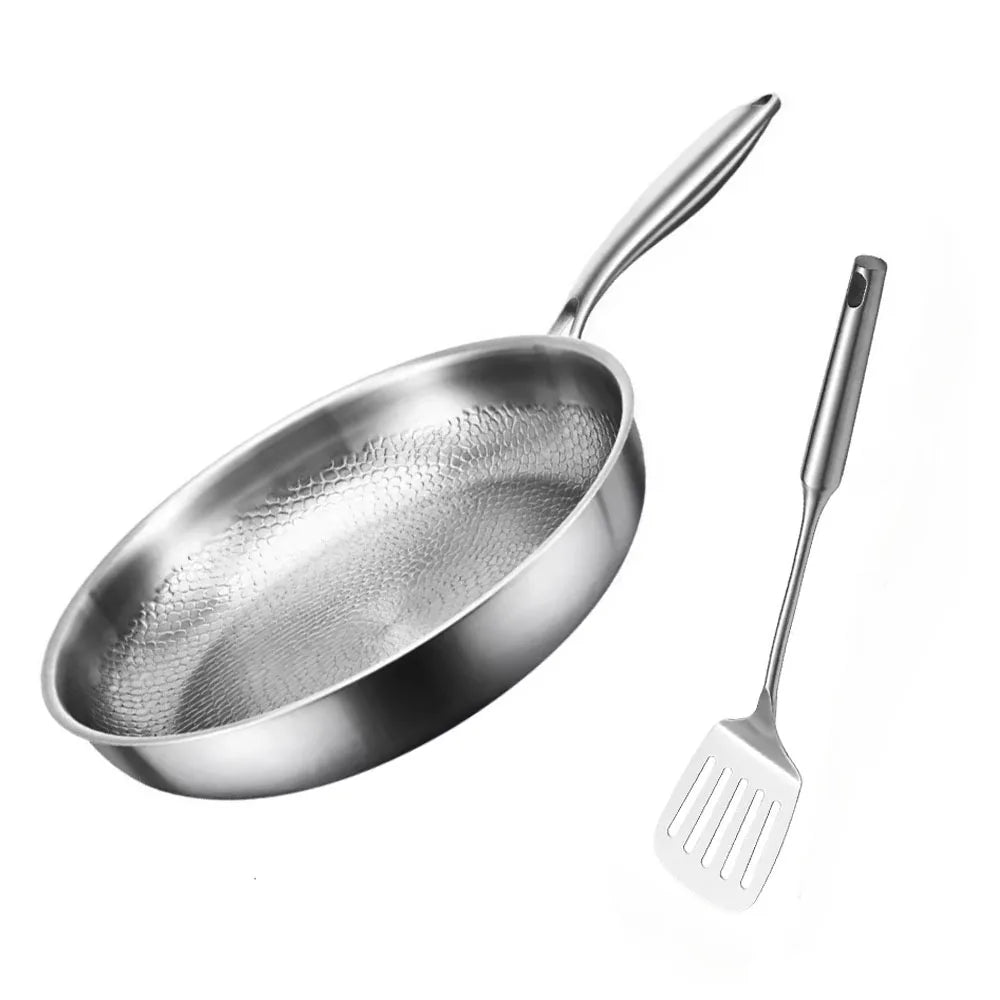 A stainless steel frying pan with a honeycomb textured interior and a matching slotted spatula on a white background.