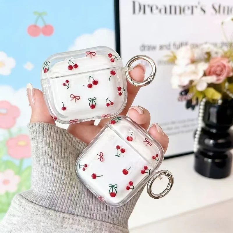 Clear, protective AirPod case featuring a red cherry and ribbon pattern, complete with a silver metal keyring loop.