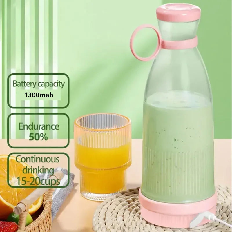Portable pink and clear electric blender bottle with a green smoothie, sitting on a woven mat next to an orange drink.