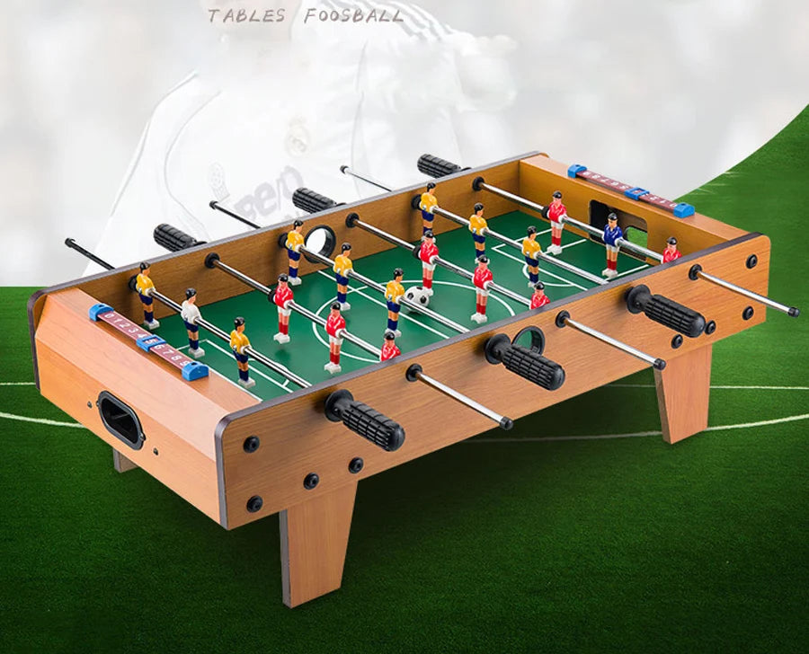 Tabletop foosball table with wood-effect finish, green pitch, black grip handles, and manual score counters.