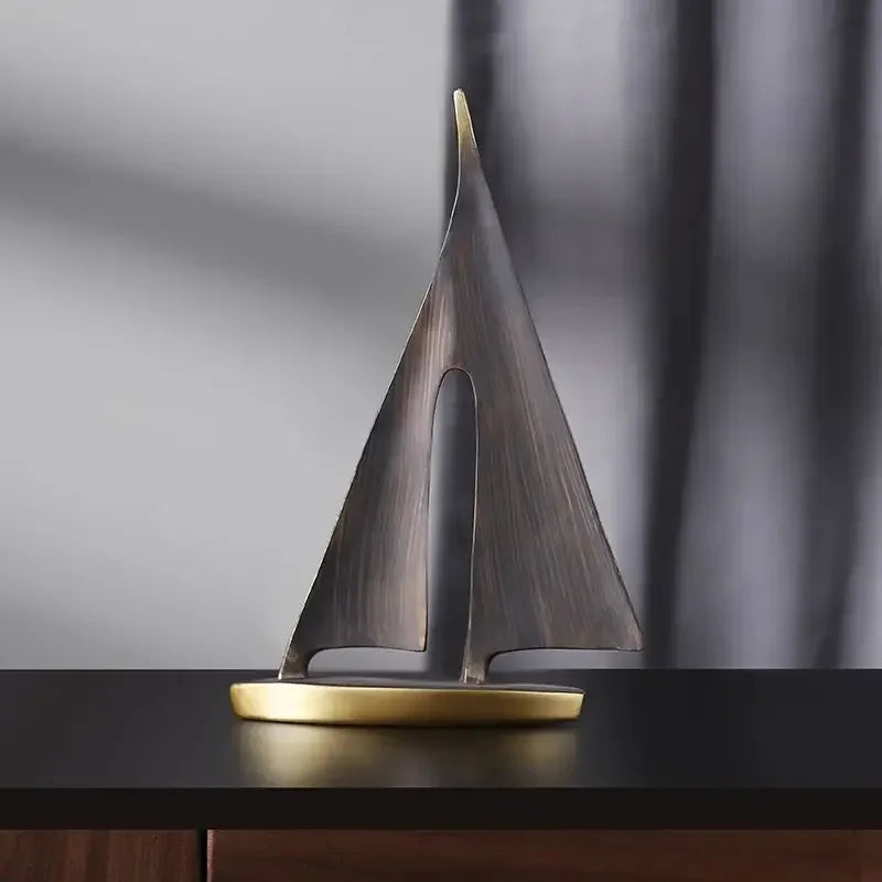 Abstract bronze-tone sailboat ornament with a gold-finish base, featuring a sleek, minimalist cut-out design.