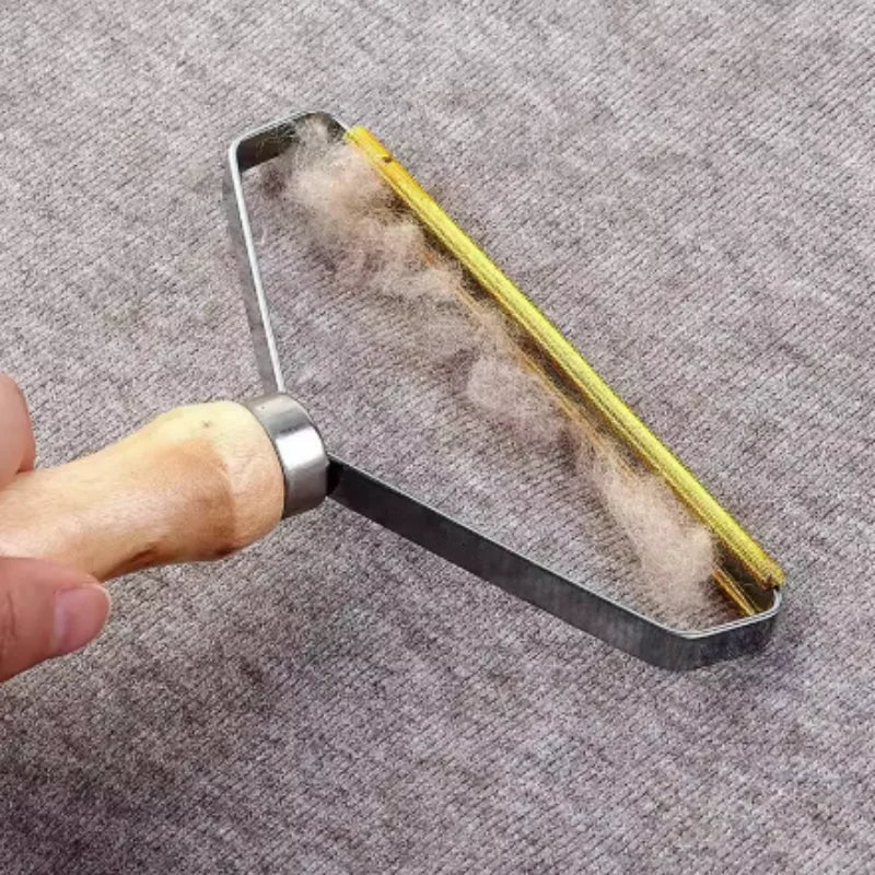 Fabric lint remover with a wooden handle and copper blade, shown lifting lint off grey fabric.